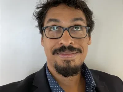 Alas Gatti Iou is a brown man in his fourties who is smiling while looking up