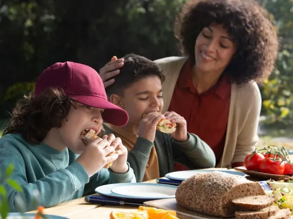 Mère et ses deux fils mangeant à une table à l'extérieur