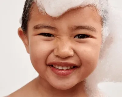 Petit garçon souriant avec de la mousse sur la tête et le visage